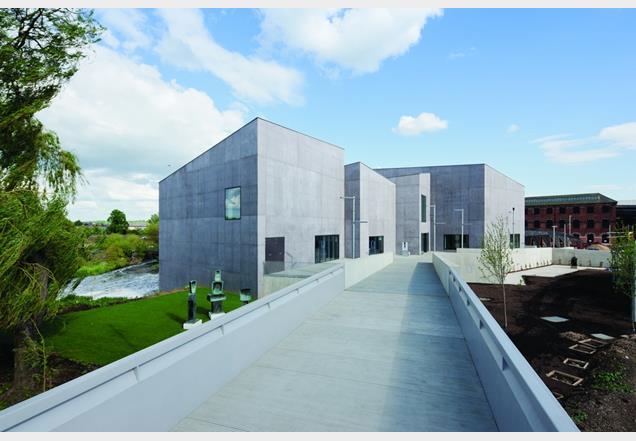 The gallery’s cluster of concrete containers are huddled at the end of a new footbridge to the town centre.